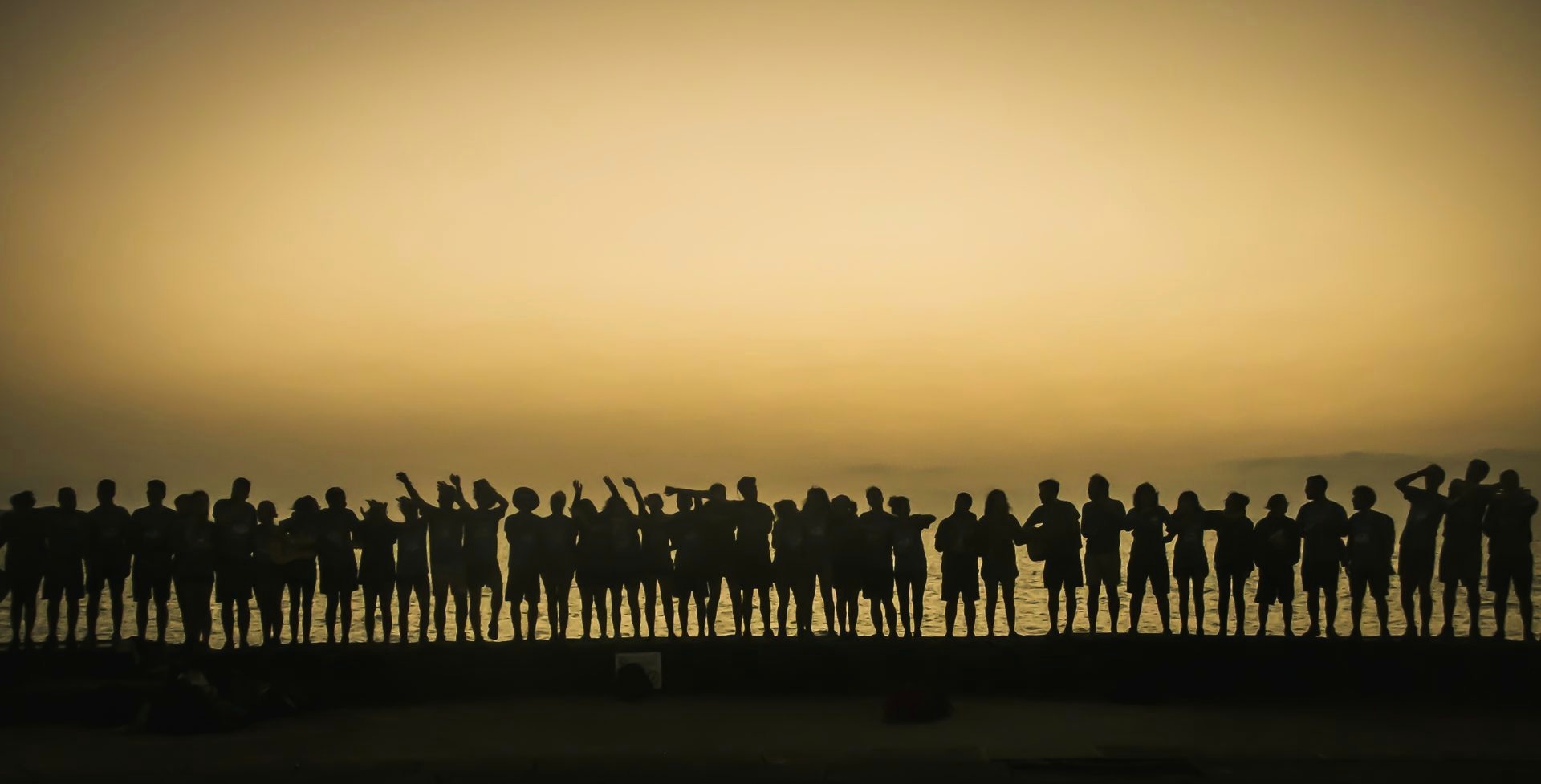 Grupo recortado en fila frente al mar al atardecer