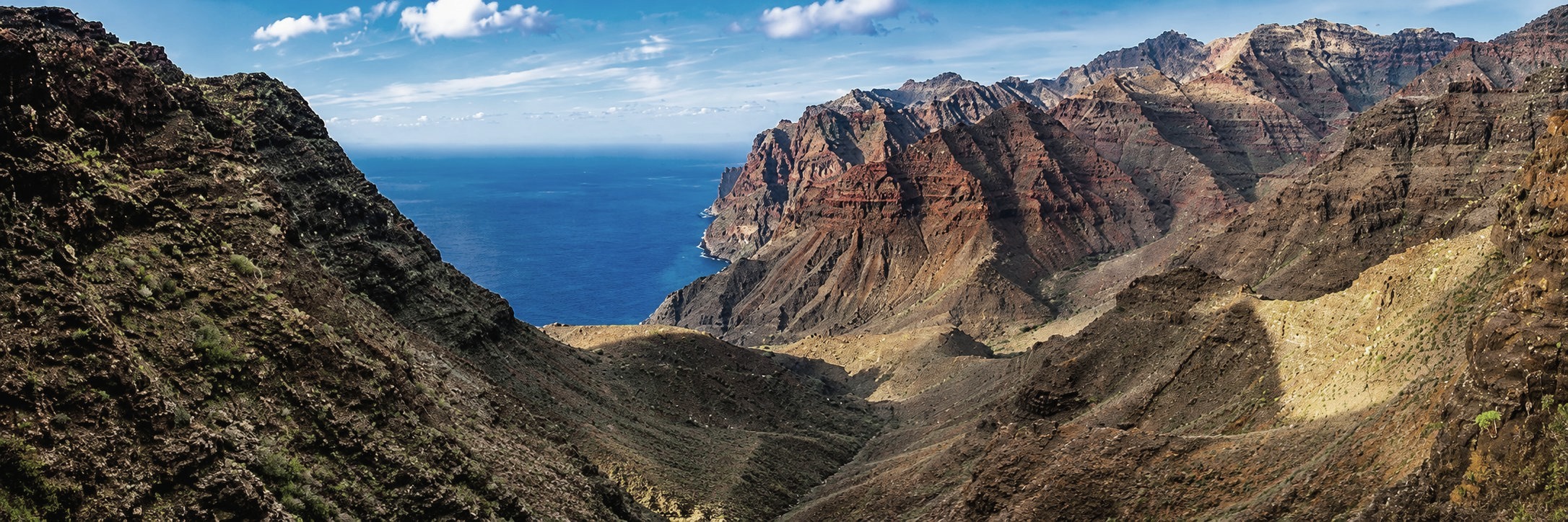 Valle de Tasártico, en Gran Canaria, con los riscos rojizos y el mar al fondo