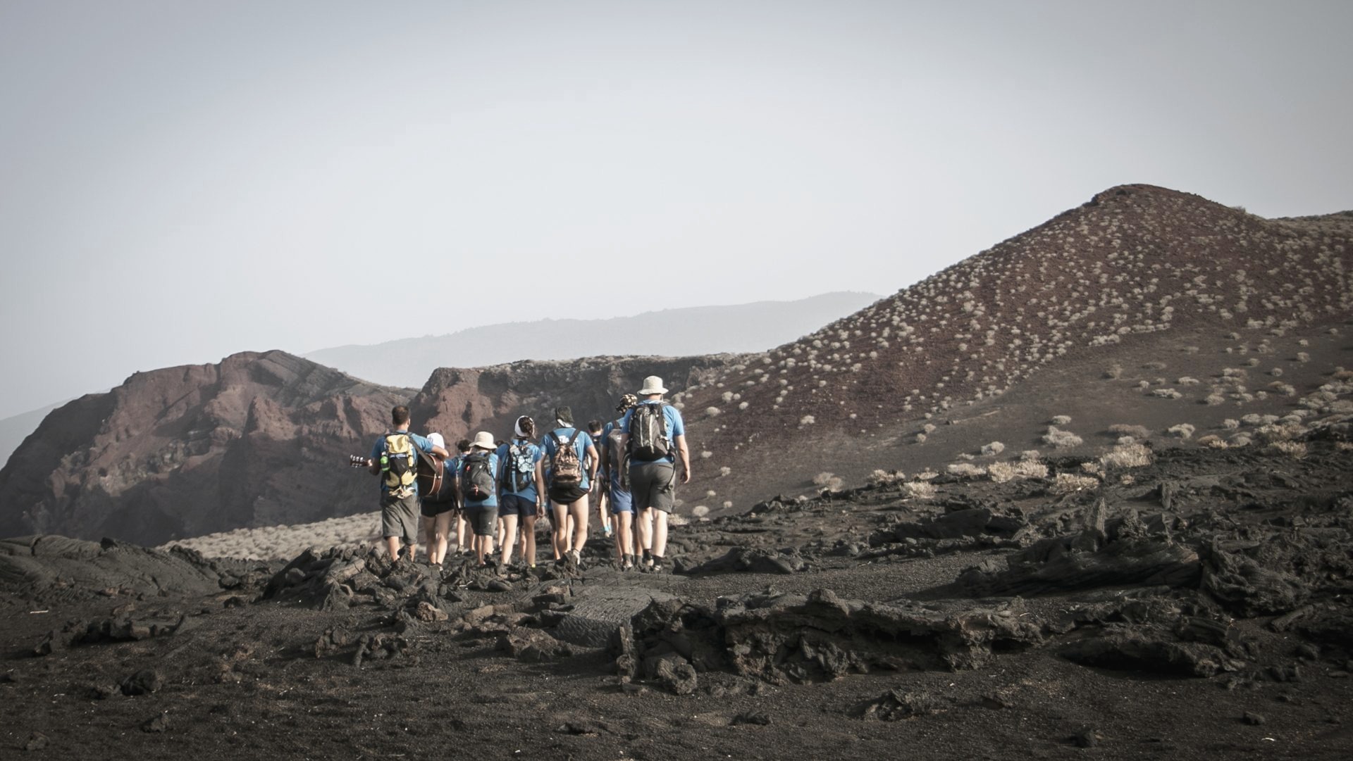 Grupo de Ruta Siete caminando en fila por un sendero volcánico de El Hierro, con el mar de bruma al fondo