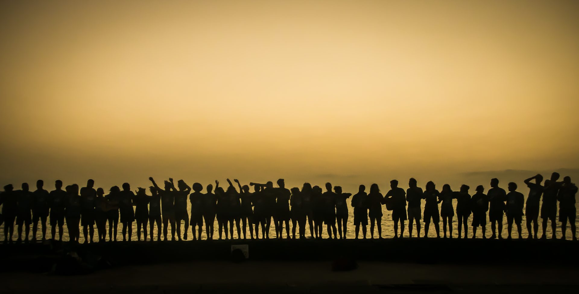 Grupo recortado en fila frente al mar al atardecer
