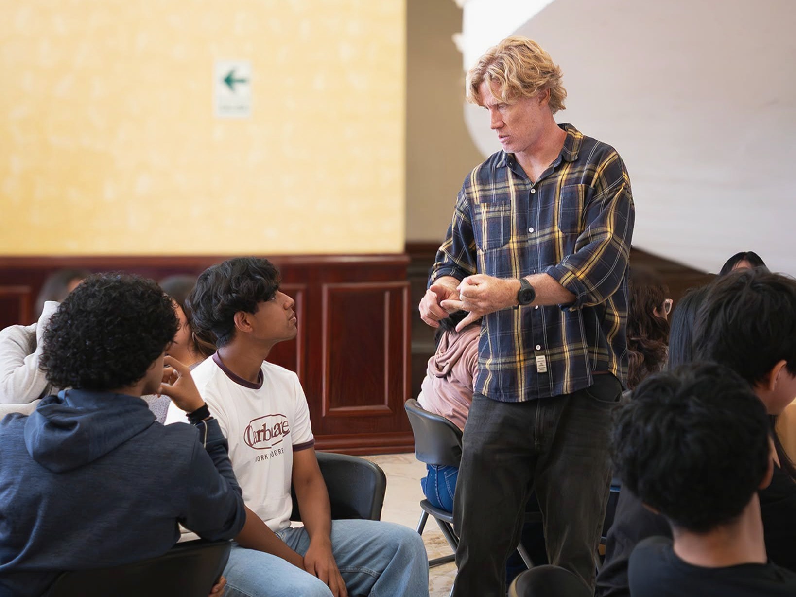 Juan Serantes hablando con estudiantes sentados en círculo durante un seminario en la Universidad de San Martín de Porres, Lima