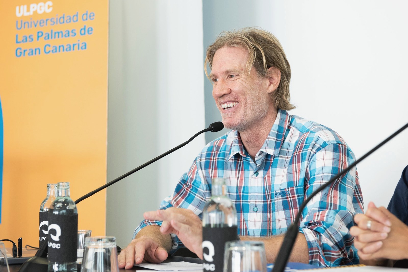 Juan Serantes riéndose al micrófono en la rueda de prensa de Ruta Siete