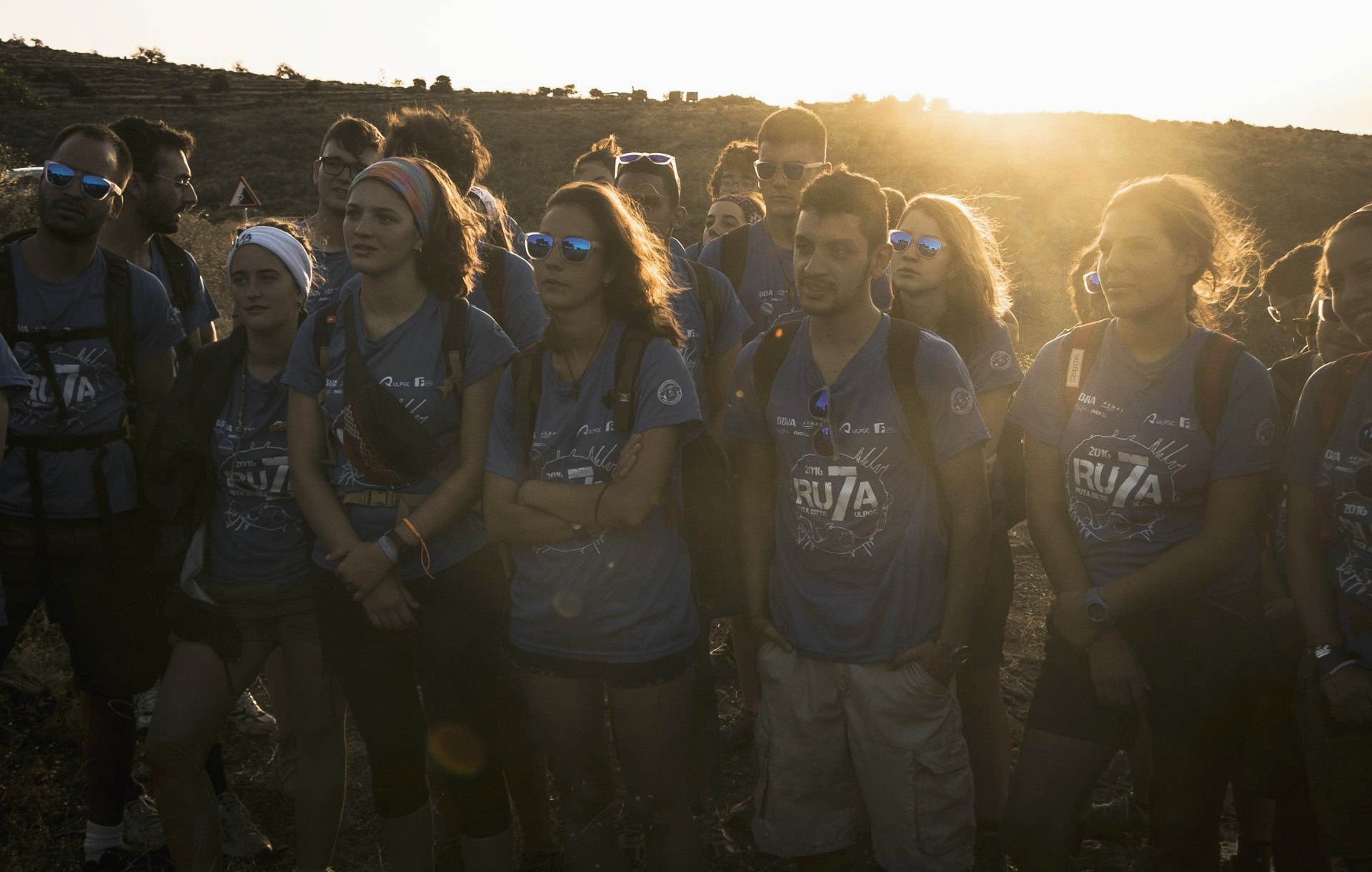 Grupo de Ruta Siete escuchando en el monte al atardecer, a contraluz